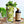 Glass with cocktail and kiwi slices as garnishes with mint leaves and a bottle of El Guapo tonic syrup on a woven tray.