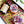 Two glasses filled with a colorful drink and sweet potato syrup bottle on a decorative tray garnished with dried flower petals