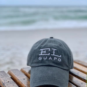 El Guapo embroidered logo baseball cap on a wooden bench at the beach.