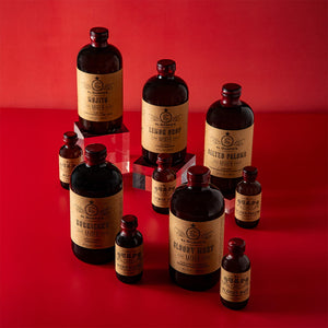 Collection of full size and single serving El Guapo Mixer bottles on a red background
